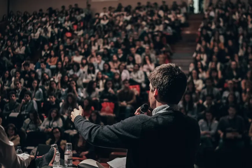 A student speaking to a packed auditorium