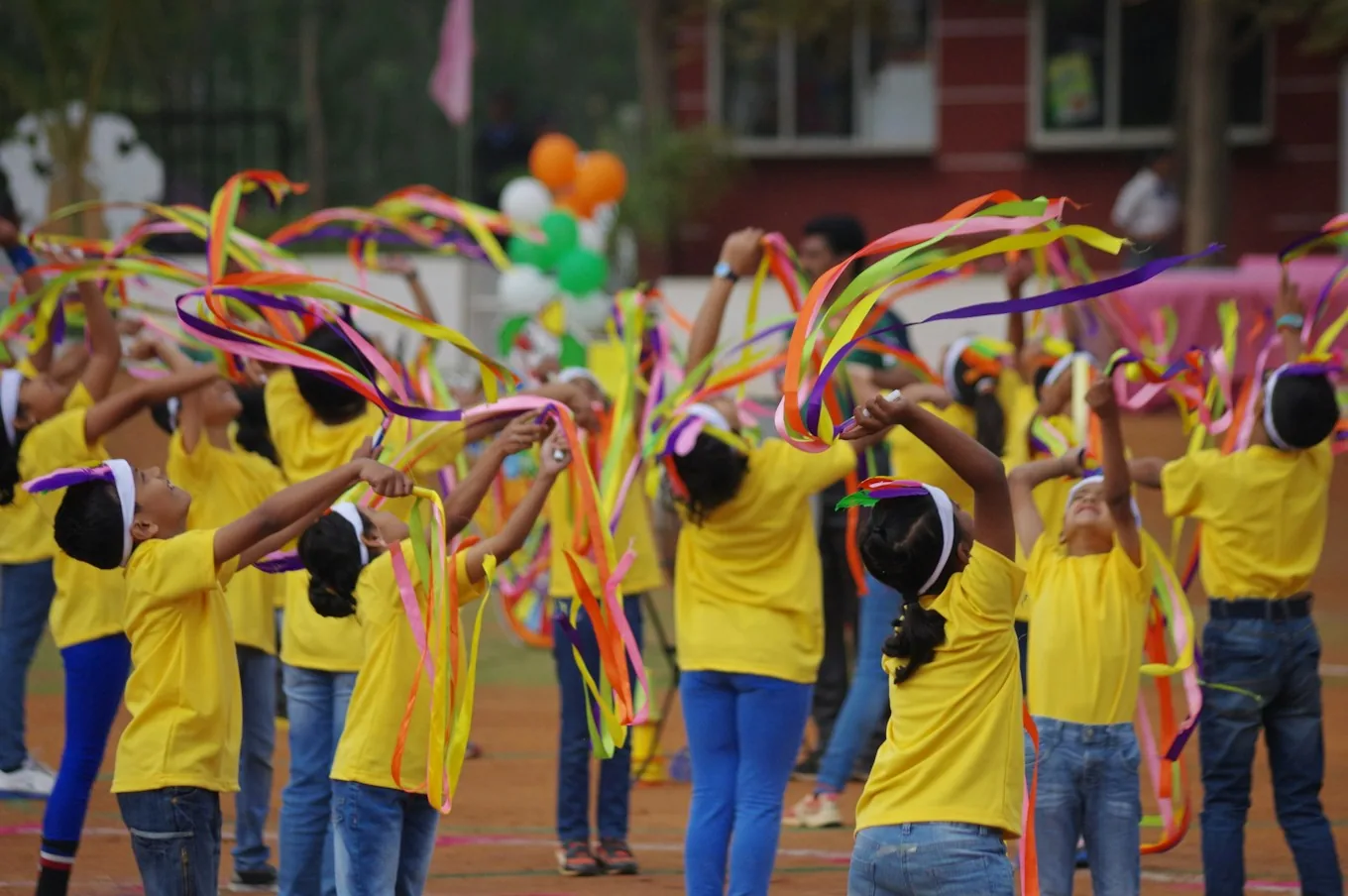 Children in yellow shirts dancing with ribbons at a performance